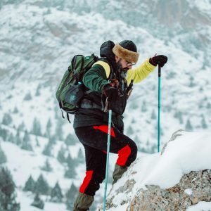 A determined mountaineer climbing a snowy slope with hiking gear.